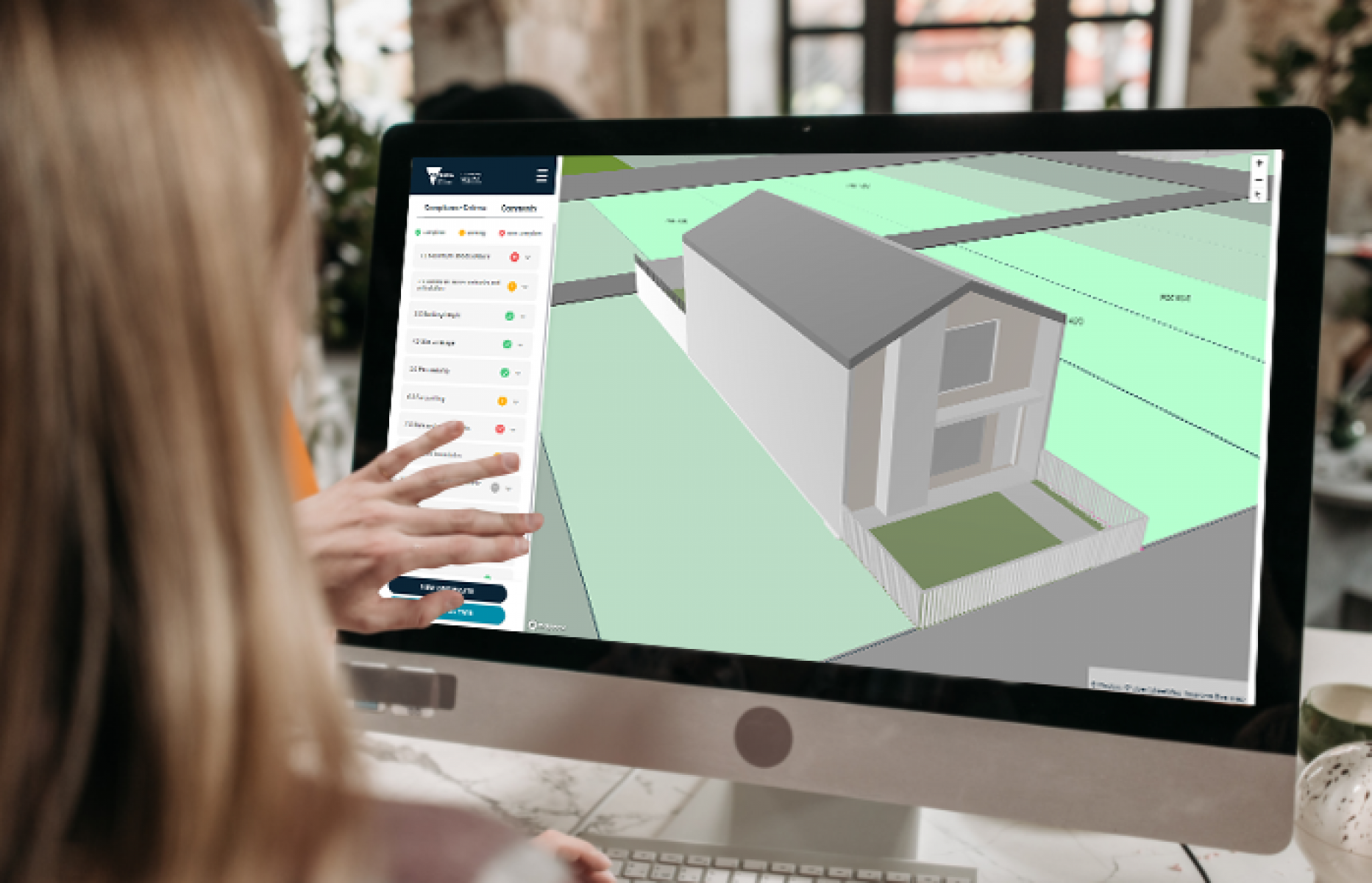 A photo looking over a woman's shoulder at an image of a 3D building on a computer monitor.