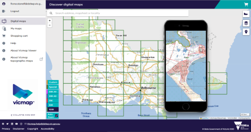 The Vicmap Viewer interface showing menu options on the left hand side and a map of the state segmented into map portions. A Mobile device is overlaid displaying detail of a Vicmap topographic map.  
